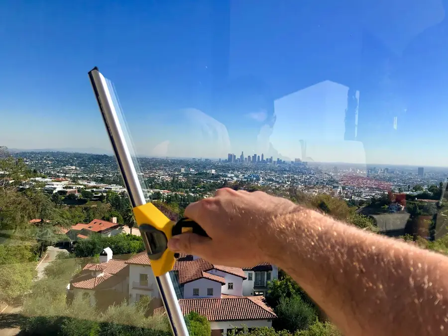 Window cleaning technician working on glass with downtown Los Angeles skyline view